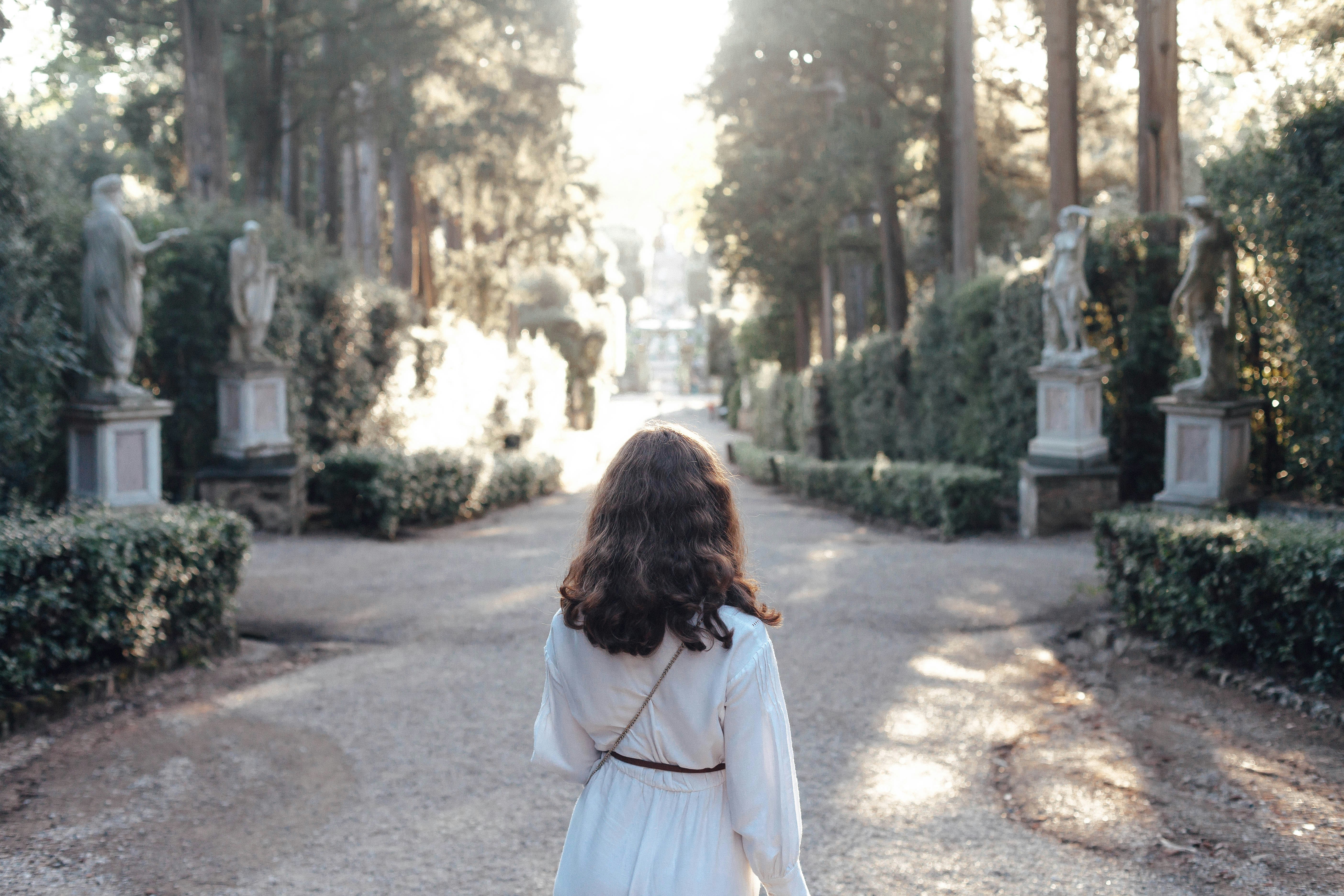 woman in white dress standing on gray concrete pathway during daytime